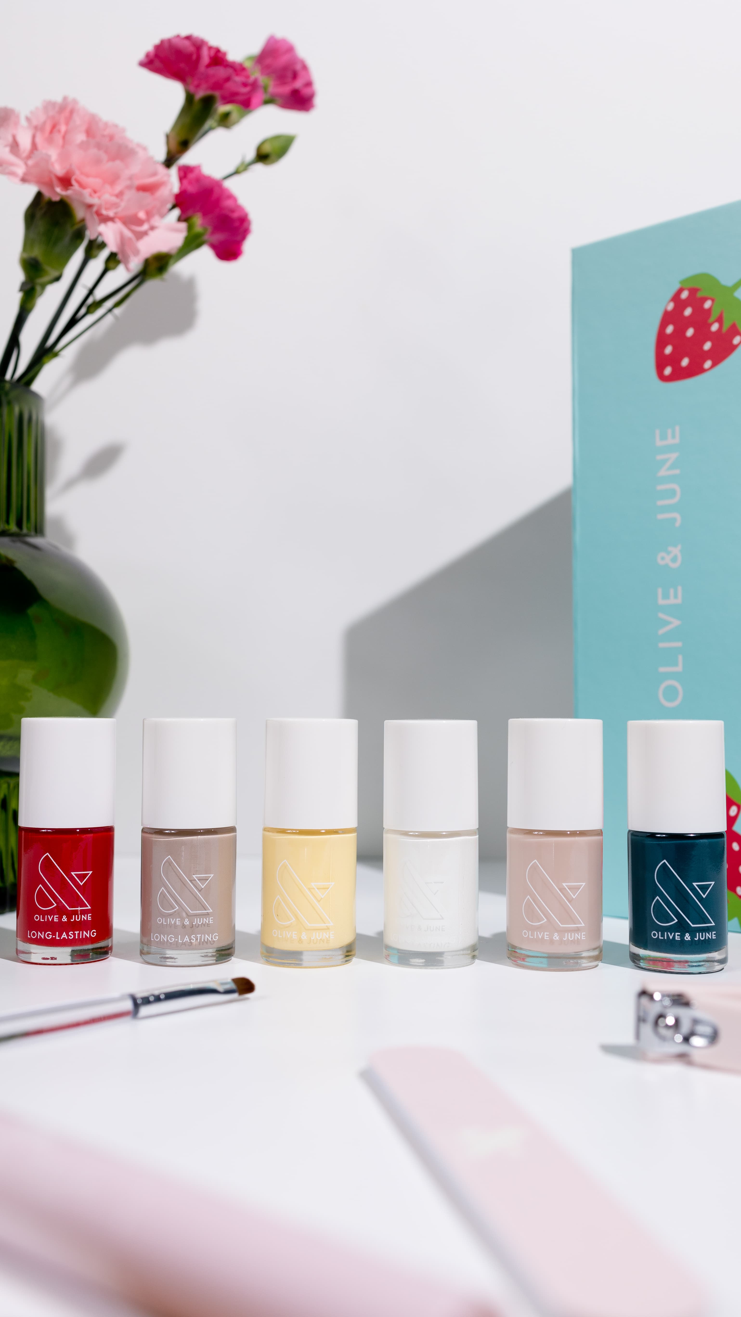 Six Olive & June nail polish bottles lined up on a white surface, shot in even studio light